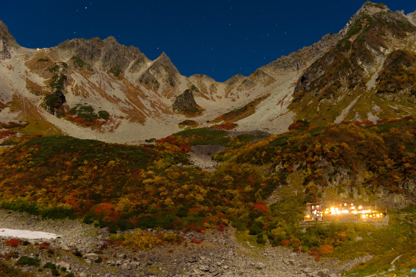星空の下で黄葉に彩られた涸沢カールの山々と山荘の明かり
