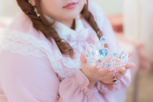 ティアラを両手に持った姫風の女性、ツインテールドレス姿