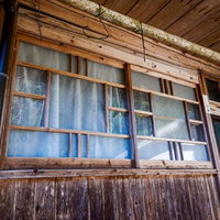 廃屋の軒下にある古びた木造建築の窓と朽ちた木材の写真