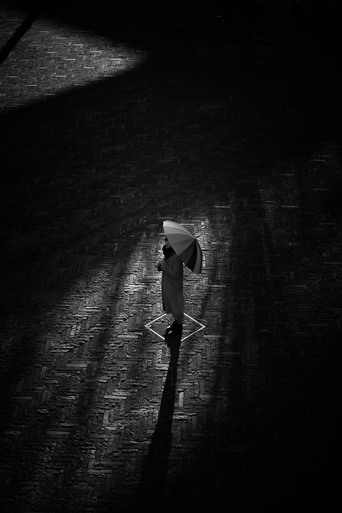 傘を持ち見上げる女性のシルエットと影が描かれた逆光アート