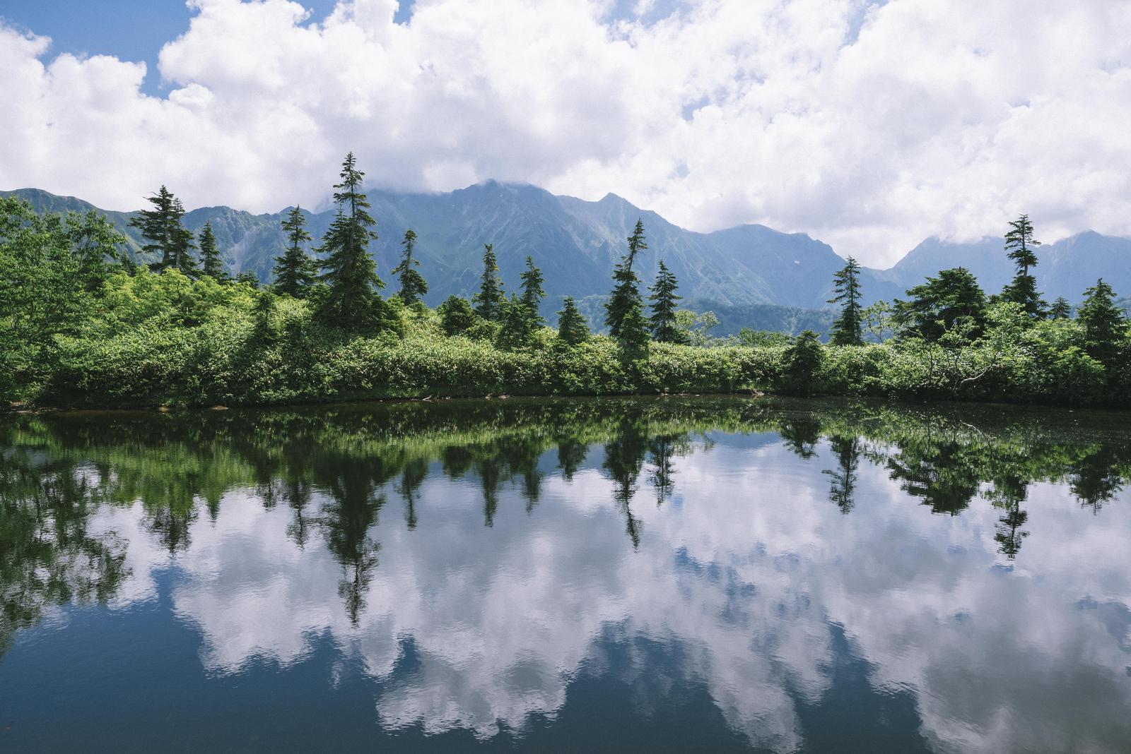 静かな池に北アルプスの山々が映り込んでいる風景