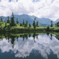 鏡池に映る笠ヶ岳と北アルプスにかかる雲の写真