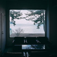 琵琶湖が見える客室の大きな窓からの景観と室内のベンチの写真