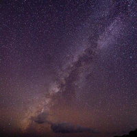 岩場の上に広がる天の川と満天の星空の写真
