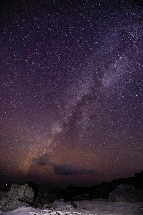 岩場の上に広がる天の川と満天の星空