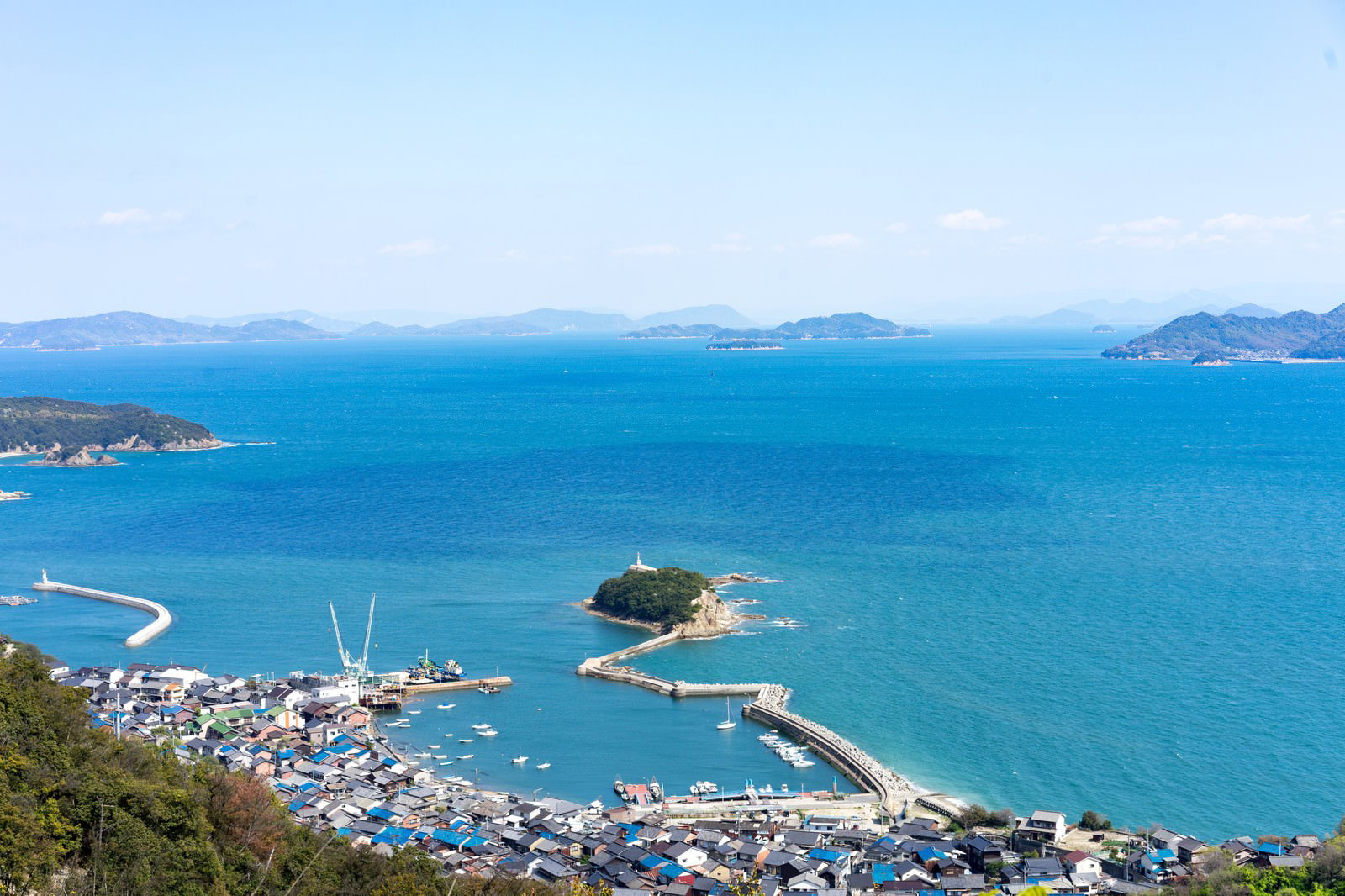 青い海に浮かぶ玉津島と福山市鞆町の港町風景、防波堤が見える海岸線