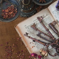 木製テーブルに並べた古い鍵と古書、紫色のドライフラワーの写真