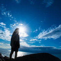 海岸に立つ女性のシルエットの写真