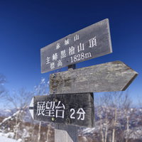 赤城山最高峰の山頂標、冬の雪化粧に立つ木製の標識の写真