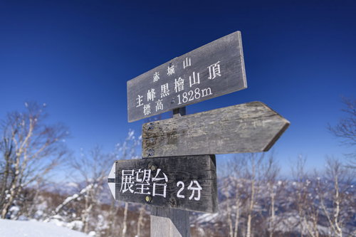 赤城山最高峰の山頂標、冬の雪化粧に立つ木製の標識
