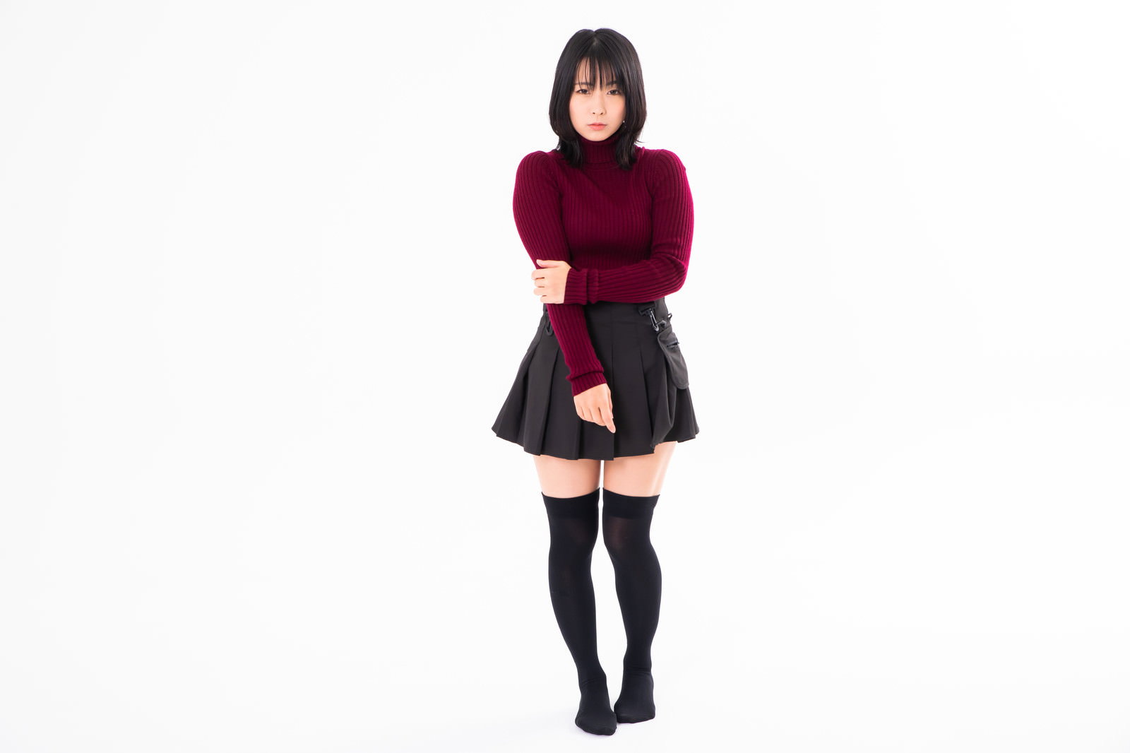 えんじ色のニットセーターを着て腕組みをして立つ女性［モデル：にゃるる］