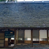 うたたねの里の古民家、茅葺屋根の縁側と伝統的なのれんの写真