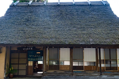 うたたねの里の古民家、茅葺屋根の縁側と伝統的なのれん