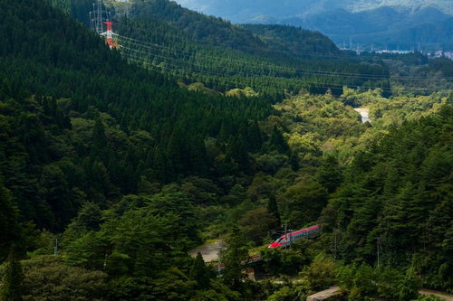 深緑の山間を走る秋田新幹線こまち号の車両と線路