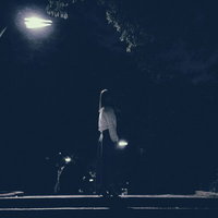 深夜に街灯の下で徘徊する女性の後姿、不気味なシルエットの写真