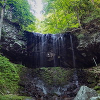 新緑の森に囲まれた岩井滝、滝の裏側から眺める裏見の滝（鏡野町）の写真