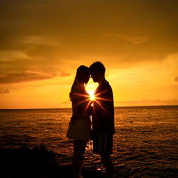夕日の海でおでこを合わせるカップルのシルエットの写真
