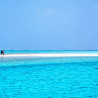 与論島の百合ヶ浜に立つ観光客の南国風景と透明な海の写真