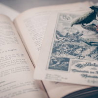 古書の上に置かれた赤いバラ（中二病末期）の写真