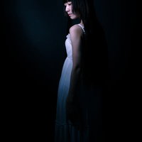 暗闇の中、うっすらとした女性の後ろ姿のシルエットの写真