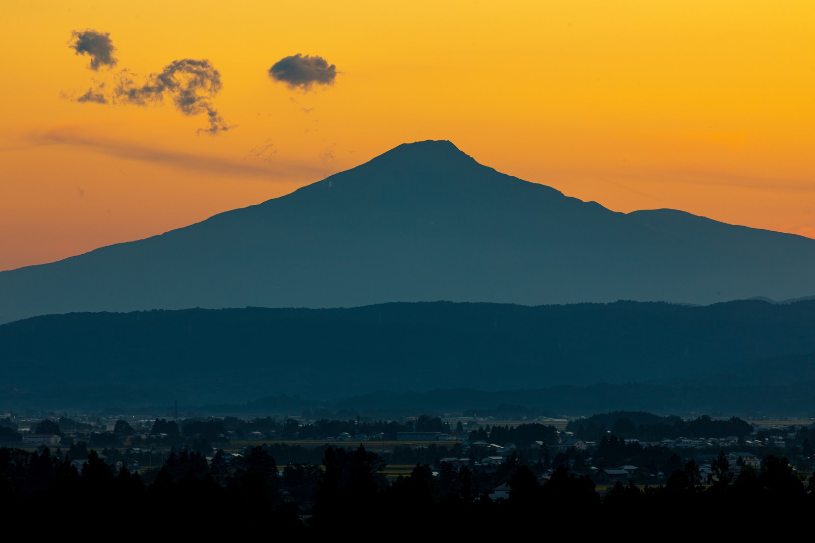 夕焼け空にシルエットで浮かび上がる鳥海山の風景