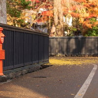 秋の武家屋敷の路地に立つ赤い郵便ポストと紅葉の写真