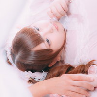 彼の手を握りしめ、ピンク系の布団で寝転ぶ彼女の写真