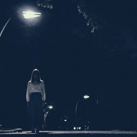 街灯の下からこちらを見つめる女性のホラーの写真