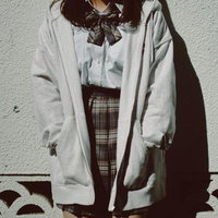 塀に寄りかかる制服姿の女子高生の写真