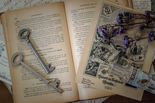 魔法使いの机に広げられた古書と鍵、ドライフラワーの物語