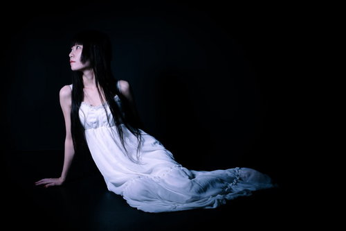 暗闇の中で切ない表情でマーメイドポーズをとる女性