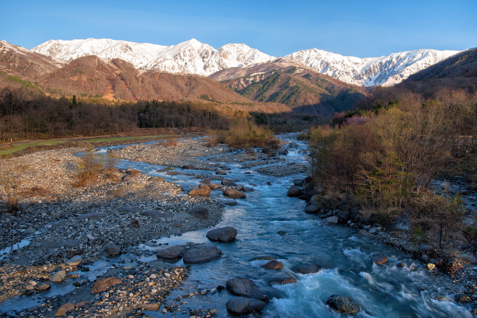 雪山を背景に松川の清流が流れる長野県白馬の風景