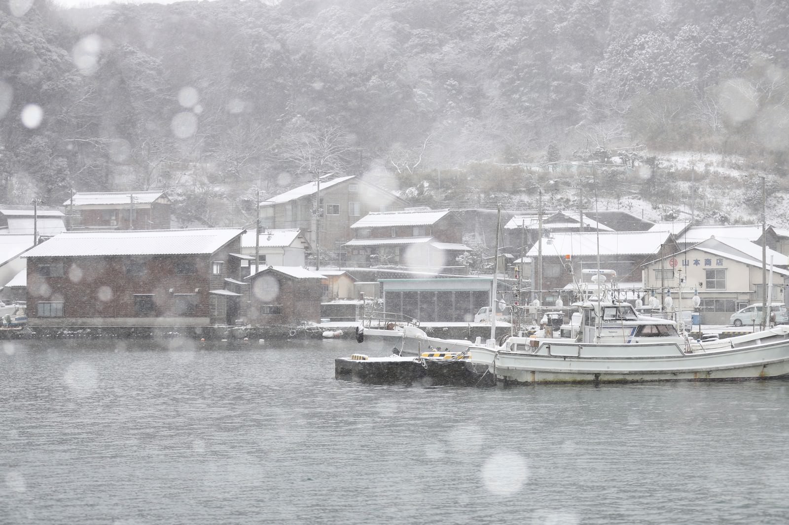 降雪の中の漁港で停泊する漁船たちをモノクロで撮影した冬景色