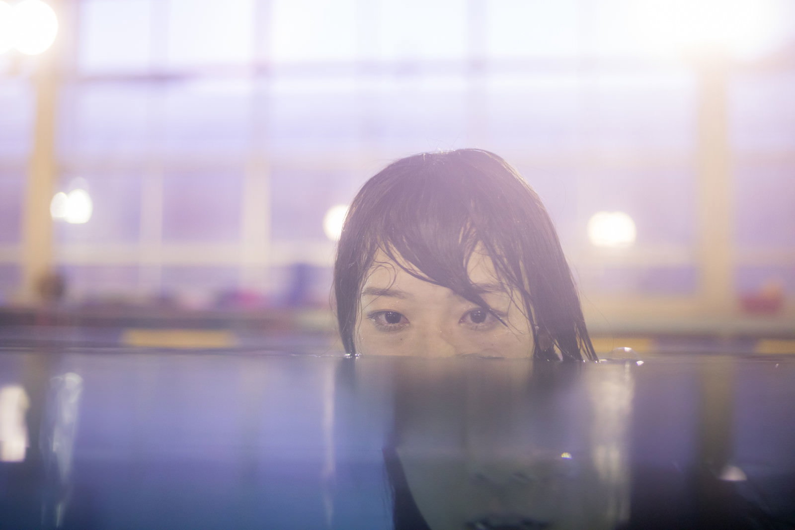 プールで水しぶきを浴びて笑う男性［モデル：たけべともこ］