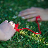 赤い糸でつながれた女性と男性の手のラブラブカップルの写真