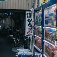軒先に自動販売機が置かれた狭い路地裏の風景の写真