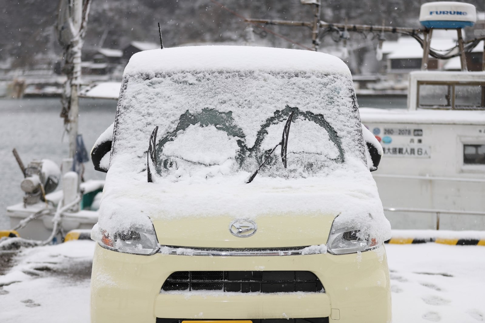 雪が積もった軽自動車のフロントガラスとワイパー跡