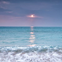 エメラルドグリーンの海に映える太陽の反射の写真