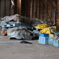 漁港の倉庫に積まれた網とロープ、漁具の保管風景の写真