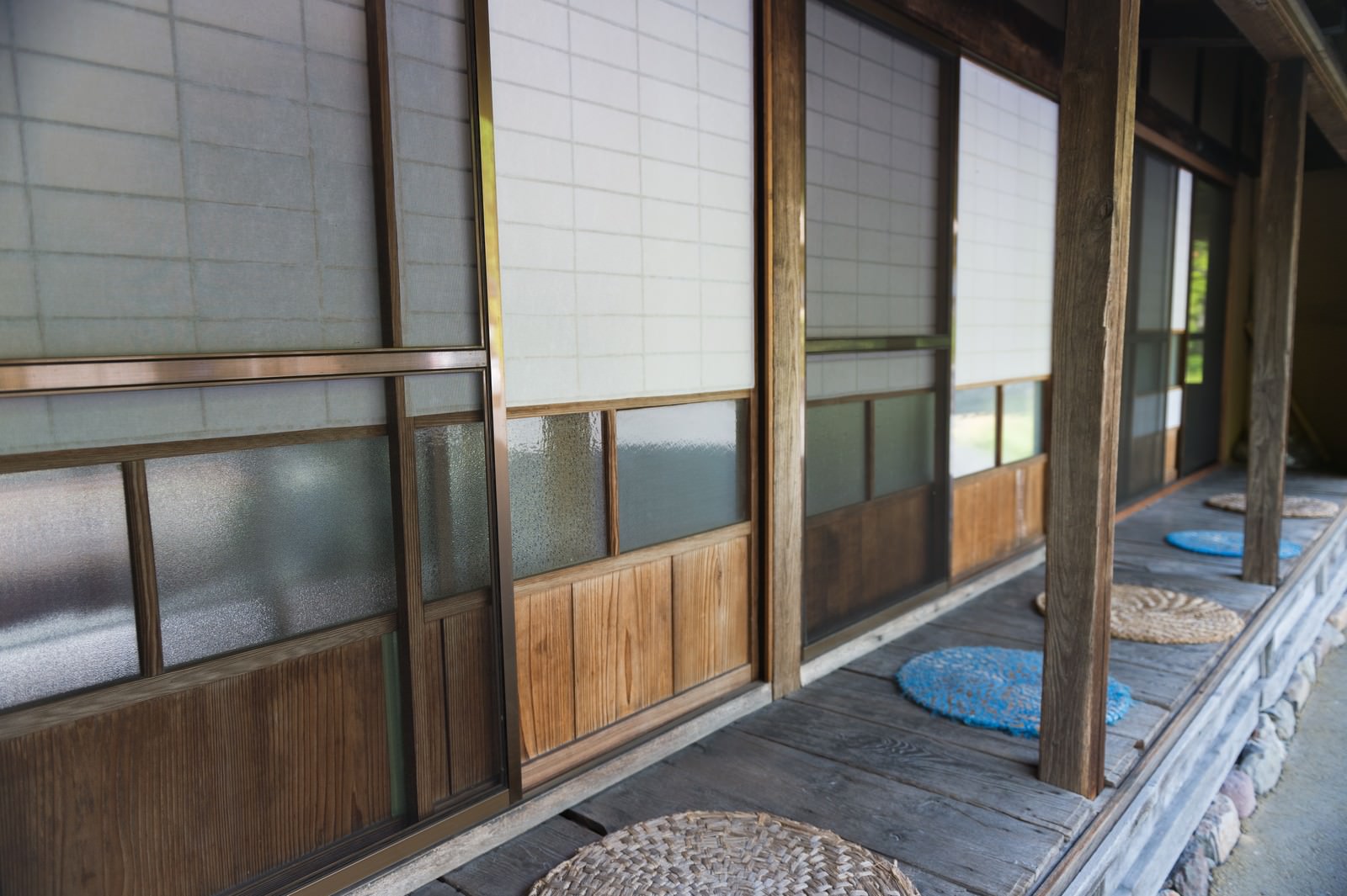 障子戸が連なる古民家の廊下、縁側から自然光が差し込む和風空間