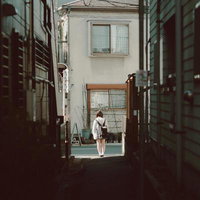 路地裏を歩む制服姿の下校JK、コンクリート舗装の狭い通学路の写真