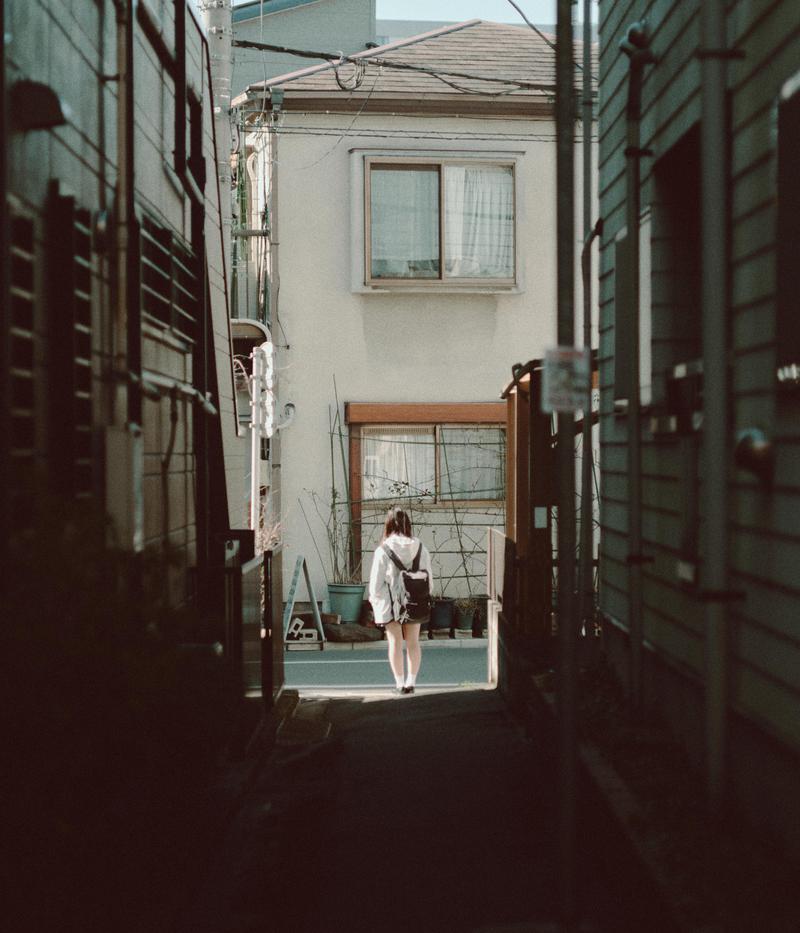 制服姿の女子高生が住宅街の路地裏を歩いている後ろ姿