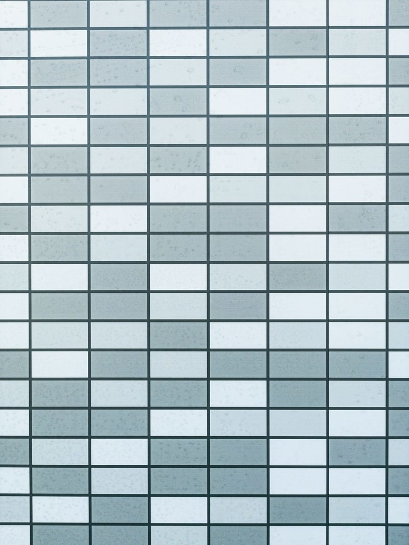 薄いブルーグレーの正方形タイルが規則正しく並んだ外壁