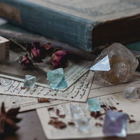 古い洋書の上に置かれたクリスタルと天然石の写真