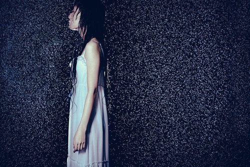 大雨にどしゃ降りされた中でほっそりした女性の横姿