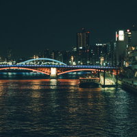 隅田川に架かるライトアップされた橋と水上バスの夜景の写真