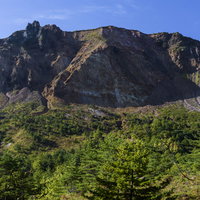 裏磐梯の荒々しい絶壁と緑の森林が広がる磐梯山の眺めの写真