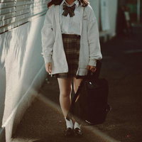 リュックを手に持つ制服姿の女性が歩む通学路での一瞬の写真