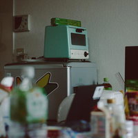 一人暮らしの狭いキッチンに並ぶ小さい冷蔵庫とオーブンの写真