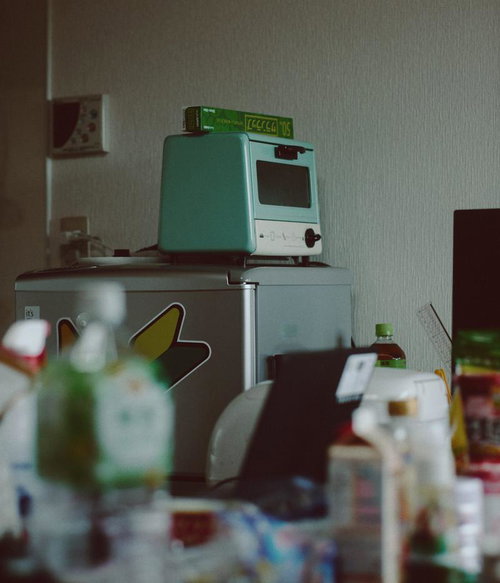 一人暮らしの狭いキッチンに並ぶ小さい冷蔵庫とオーブン